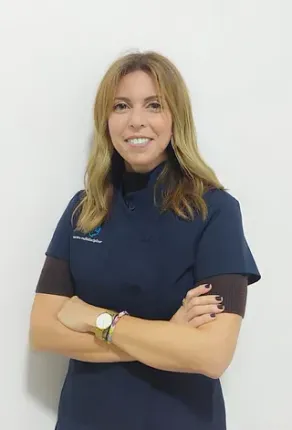 Una mujer con un uniforme azul posa para una fotografía con los brazos cruzados.